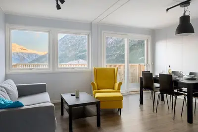 a living room with a table and a yellow chair at Hardangerpark AS in Kinsarvik