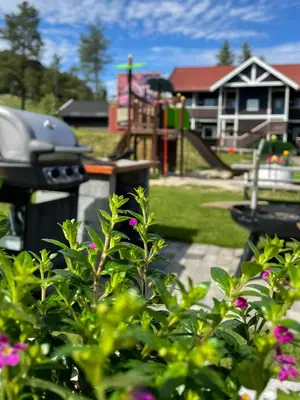 a garden with a playground and a house at Trysilfjell Apartment Hotel in Trysil