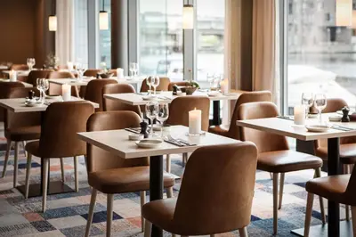 a restaurant with tables and chairs and a window at Scandic Nidelven in Trondheim