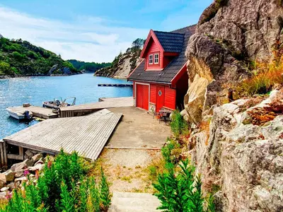 a red house sitting on the side of a body of water at 6 person holiday home in Urangsvåg in Steinsbø