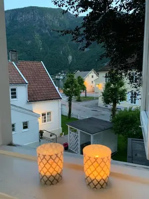 two orange stools on a balcony with a view of a house at Høyanger 3 roms leilighet in Høyanger