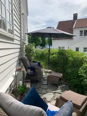 a patio with a couch and an umbrella and chairs at Høyanger 3 roms leilighet in Høyanger