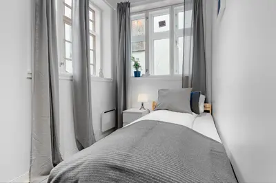 a white bedroom with a bed and two windows at Fabryka in Bergen