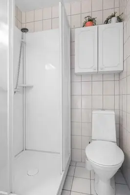 a white bathroom with a toilet and a shower at Fabryka in Bergen