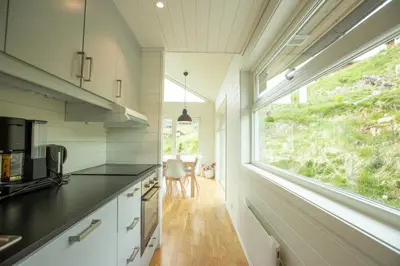a kitchen with white cabinets and a large window at Fjellsporthytta nr. 4 in Sogndal
