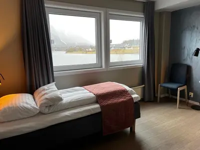 a bedroom with two windows and a bed and a chair at Frichs Ekspress Åndalsnes in Åndalsnes