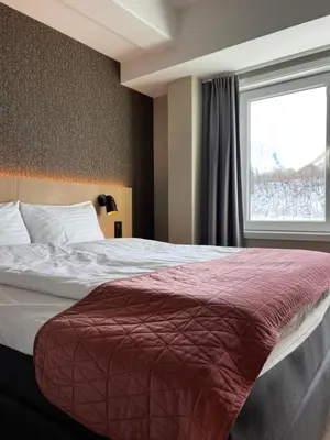 a bedroom with a large bed with a window at Frichs Ekspress Åndalsnes in Åndalsnes