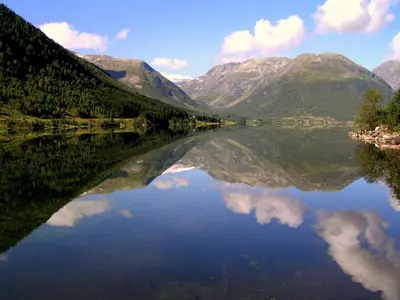 a reflection of the mountains in a body of water at Timblalodgen in Sogndal
