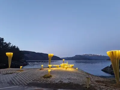 a group of tables and chairs next to a body of water at Ropeid Fjordferie in Ropeid