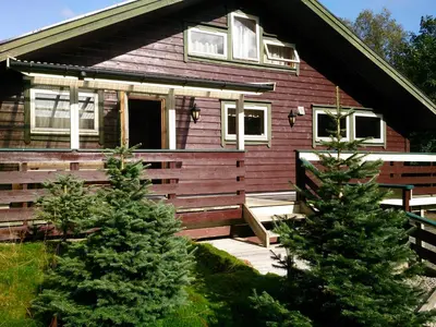 a house with two pine trees in front of it at Ropeid Fjordferie in Ropeid