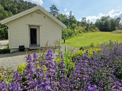 a garden with purple flowers in front of a building at Ropeid Fjordferie in Ropeid