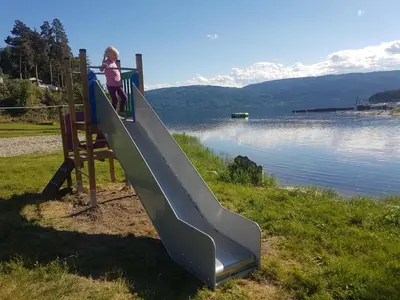 a child on a slide next to a body of water at Utvika Camping in Nes