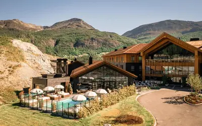 a resort with a pool and mountains in the background at Fýri Resort in Hemsedal
