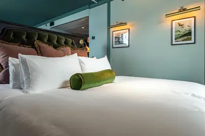 a large white bed with a green pillow on it at Fýri Resort in Hemsedal