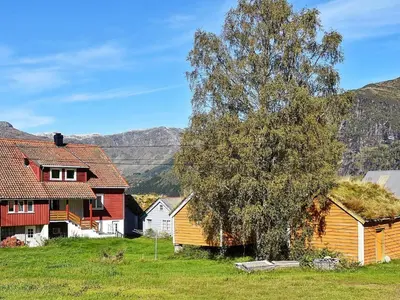 a group of houses and a tree in a field at 10 person holiday home in skei i jølster in Årdal