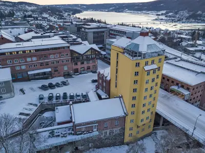 a yellow building with snow on it in a city at Aksjemøllen - by Classic Norway Hotels in Lillehammer