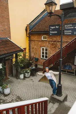 a woman is standing on a ledge next to a street light at Aksjemøllen - by Classic Norway Hotels in Lillehammer