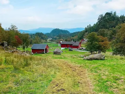 an open field with red barns in the mountains at 9 person holiday home in Reksteren in Haukafer