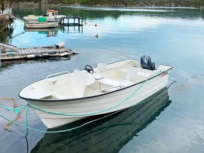 a white boat tied to a dock in the water at 9 person holiday home in Reksteren in Haukafer