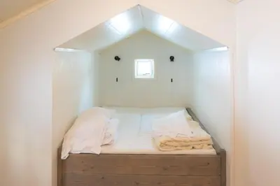 a small bed in a white room with a window at Fjelltun 6-sengs in Trysil