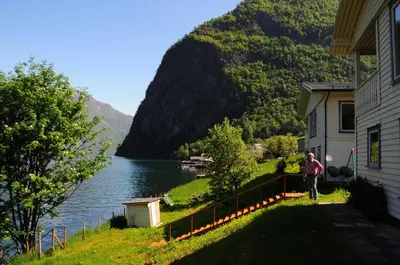 a person walking next to a house next to a lake at Visit Undredal in Undredal
