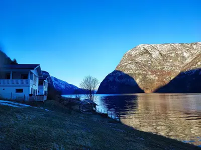 a house on a hill next to a body of water at Visit Undredal in Undredal