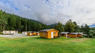 a group of cabins in a field with trees at Korsbakken Camping in Isfjorden
