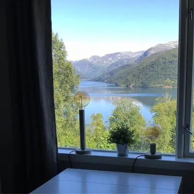 a window with a view of a lake and mountains at Studioleilighet i Haukedalen in Holsen