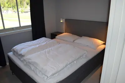 a bed with white sheets and pillows in a bedroom at Einemo Apartments in Lærdalsøyri