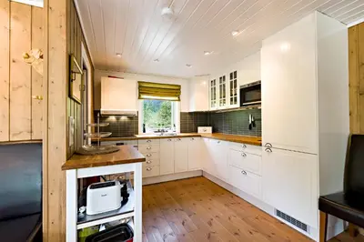 a kitchen with white cabinets and a wooden floor at Riverside in Hornindal