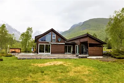 a wooden house with mountains in the background at Riverside in Hornindal