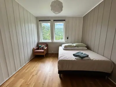 a bedroom with a bed and a chair and a window at Trolltunga Lodge in Odda