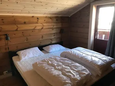 a bed in a room with a wooden wall at Harpefossen Skisenter og Hyttegrend in Nordfjordeid