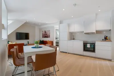 a kitchen and living room with a white table and chairs at Barfot Apartments in Bergen