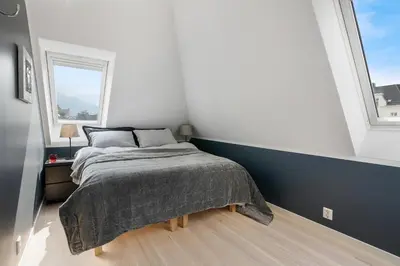 a bedroom with a bed and two windows at Barfot Apartments in Bergen