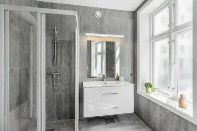 a bathroom with a sink and a shower and a mirror at Barfot Apartments in Bergen