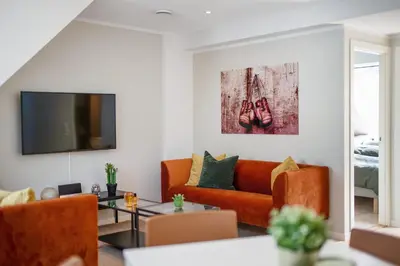 a living room with an orange couch and a flat screen tv at Barfot Apartments in Bergen