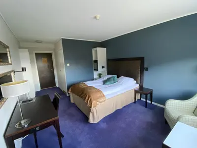 a hotel room with a large bed and a desk at Hotell Koselig in Kyrksæterøra