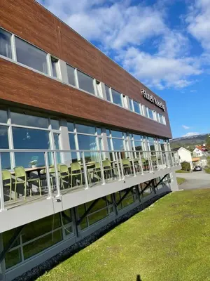 a building with tables and chairs outside of it at Hotell Koselig in Kyrksæterøra