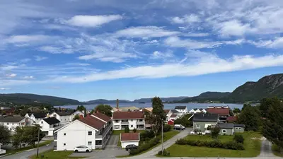 a town with houses and a lake and mountains at Hotell Koselig in Kyrksæterøra