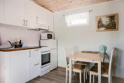 a kitchen with a table and a small kitchen with white cabinets at Fossen Accommodation in Geiranger