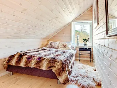 a bedroom with a large bed in a log cabin at Serene Waterfront Retreat-By Traum in Valevåg