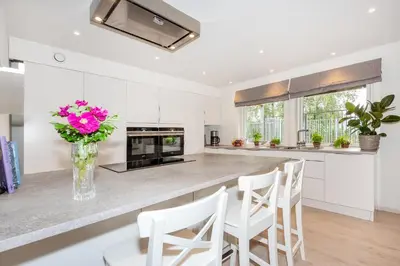 a kitchen with white cabinets and a counter with a vase of flowers at Modern Apartment with panorama wiew in Blakset