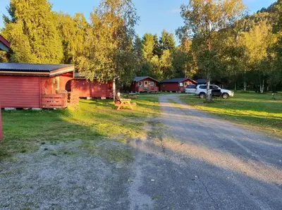 a dirt road with a house and a car parked in a field at Romsdalseggen Camping in Isfjorden