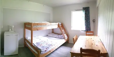 a bedroom with two bunk beds and a table at Romsdalseggen Camping in Isfjorden