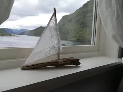 a small sail boat sitting on a window sill at Old School på Eidslandet - exclusive apartment in Eidslandet