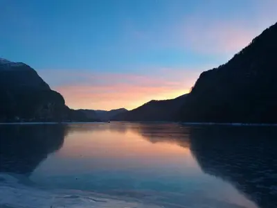 a view of a lake at sunset with mountains at Old School på Eidslandet - exclusive apartment in Eidslandet