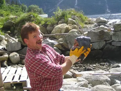 a man is holding a catchers mitt on a river at Fjordperlen in Eidfjord