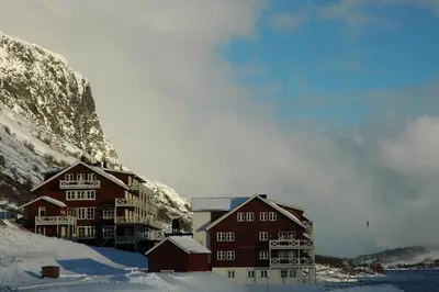 a large building in the snow next to a mountain at Nystuen in Tyinkrysset
