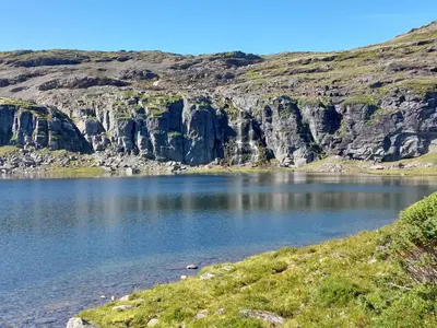 a view of a lake with cliffs in the background at Nystuen in Tyinkrysset